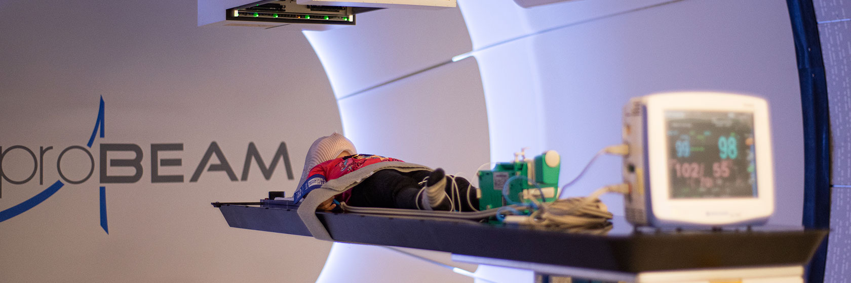 A child receives proton therapy for a tumor in his head at a gantry