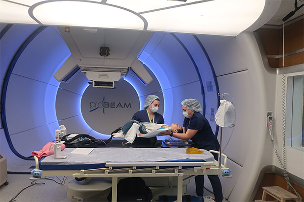 A child on a gantry unit at a proton therapy center